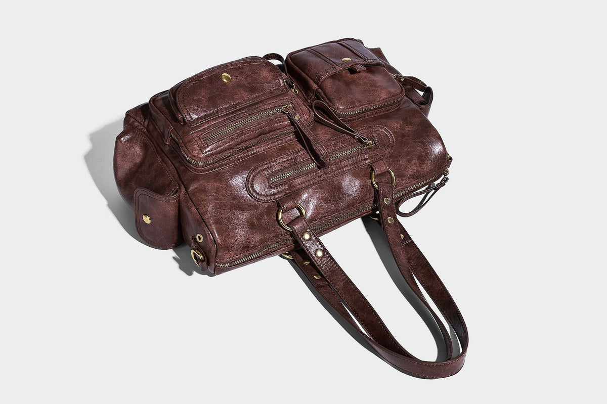 Distressed leather-look vintage satchel shoulder bag with multiple front zip pockets, dual top handles, and brass-tone