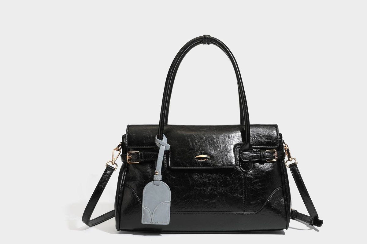 Structured glossy leather-look satchel bag with flap closure, gold-tone buckle accents, double top handles, detachable