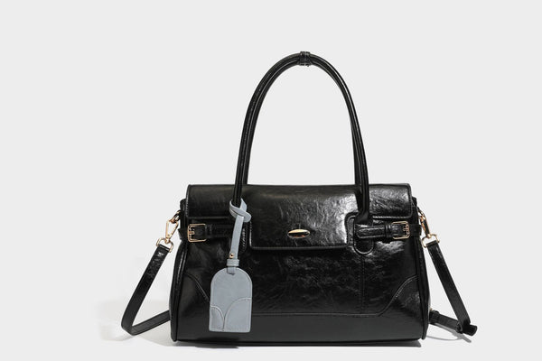 Structured glossy leather-look satchel bag with flap closure, gold-tone buckle accents, double top handles, detachable