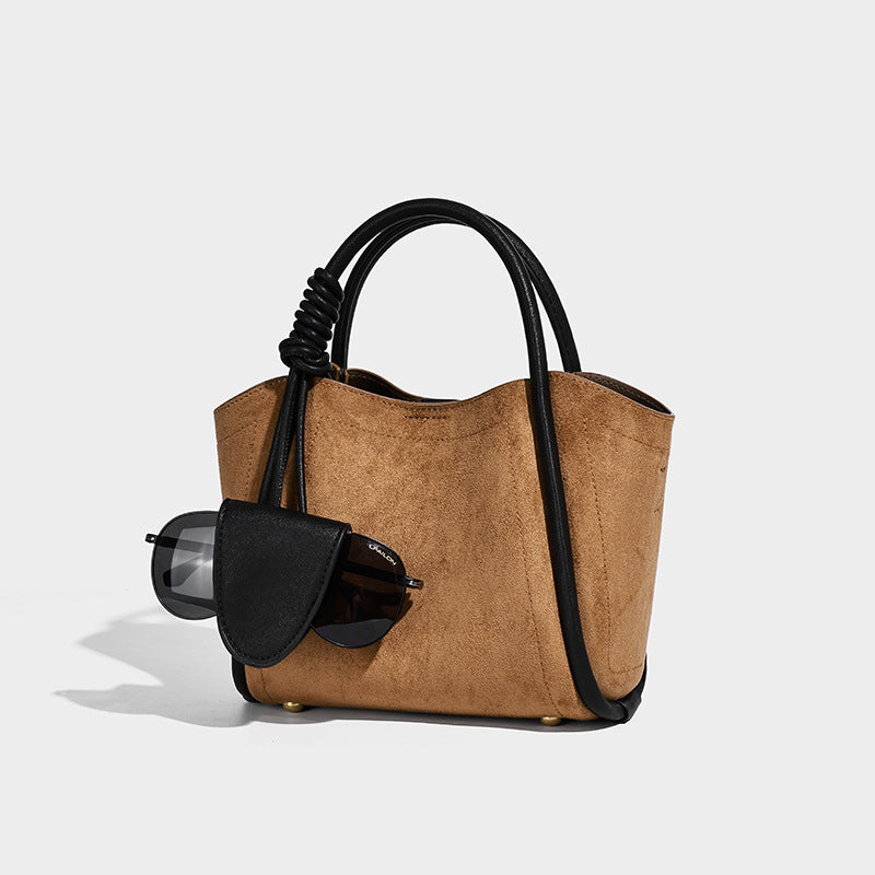 Kleine, strukturierte Tote-Bag mit offenem Oberteil aus dunkelbrauner, matter Wildlederoptik, schwarzen geknoteten Tragegriffen und angesetztem Frontdetail