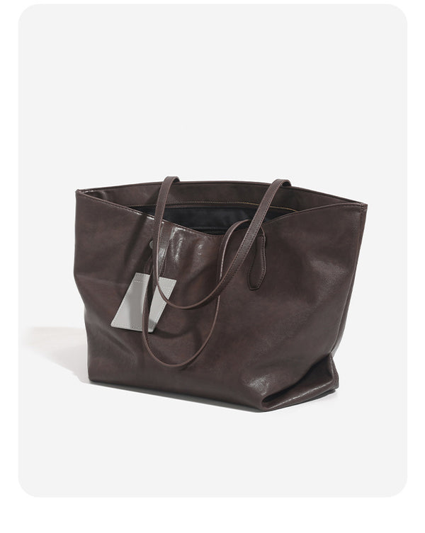 Large leather-look tote bag with trapezoid silhouette, double shoulder straps, and detachable hanging tag, detail view 9