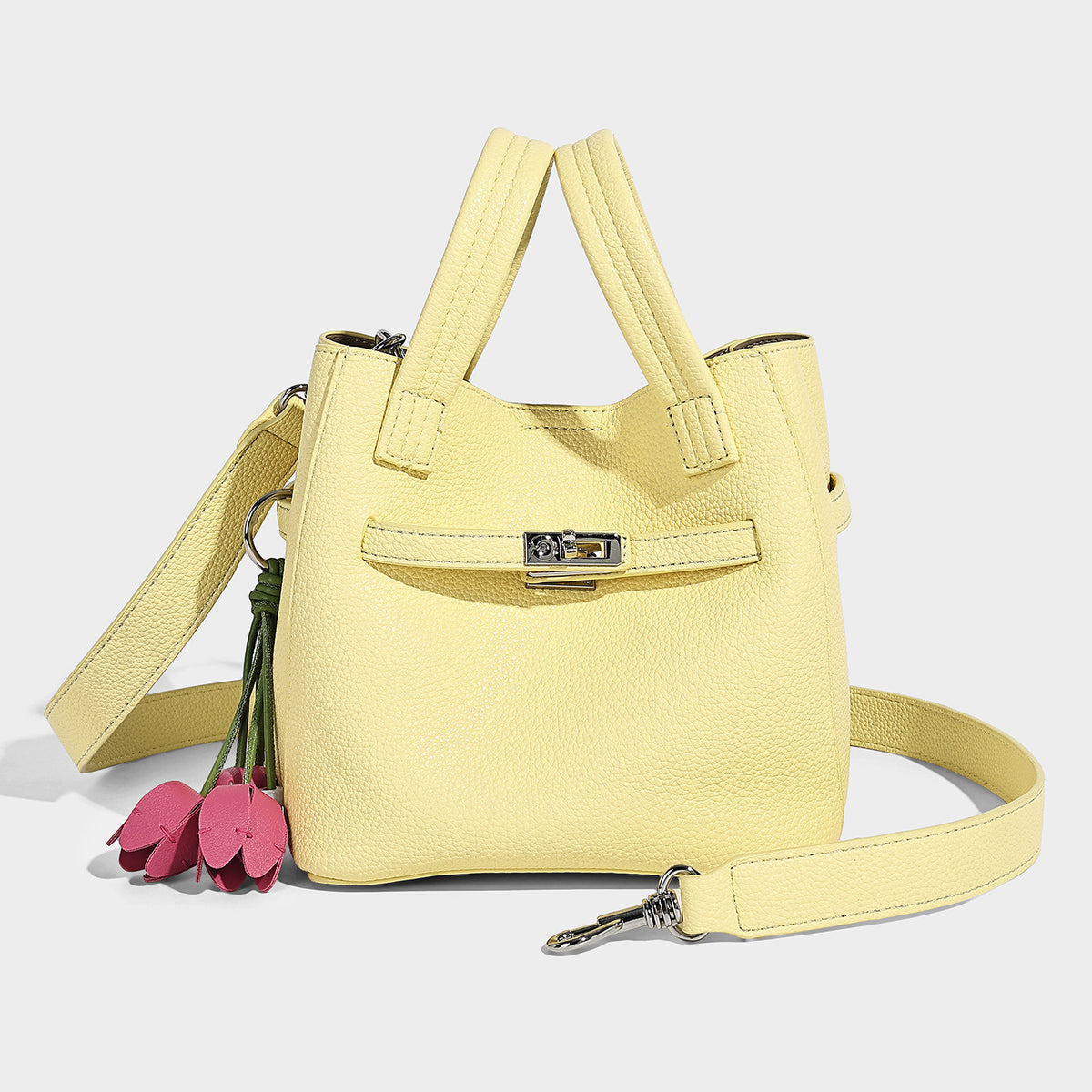 Small structured pebbled bucket tote bag with dual top handles, silver turn-lock front pocket, and detachable shoulder strap