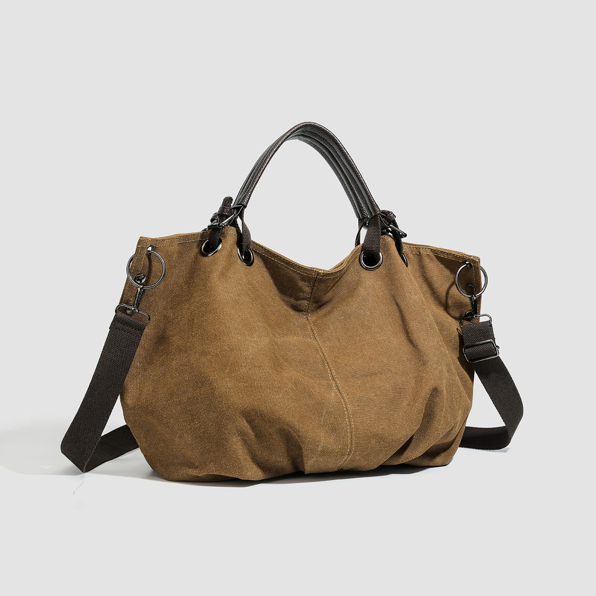 Lässig fallende Tote-Bag aus mattem Canvas mit zwei dunklen Tragegriffen oben, Metallösen und abnehmbarem langem Schulterriemen, Detailansicht