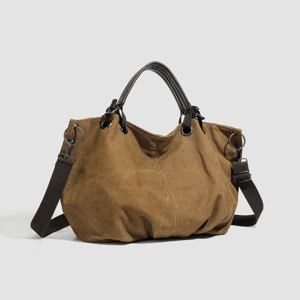Slouchy matte canvas tote bag with dark dual top handles, metal grommet hardware, and detachable long shoulder strap, detail