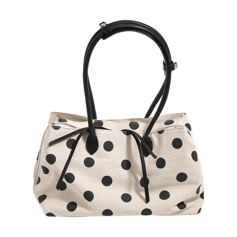 Cream canvas tote bag with black polka dots, rounded leather-look handles, and zip-top closure, detail view 5