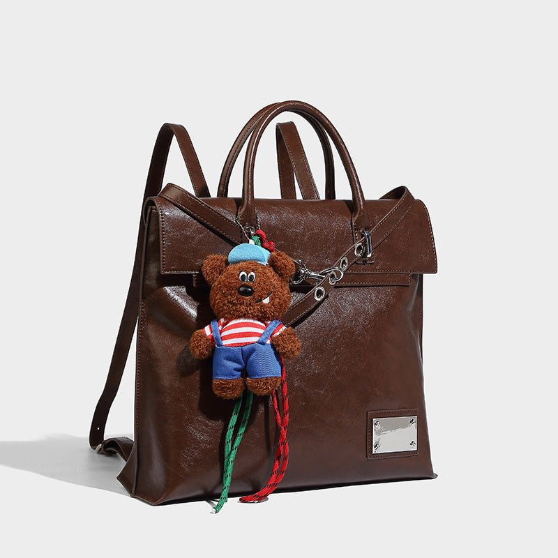 Large glossy leather-look convertible tote backpack with plush bear charm and silver hardware, front view