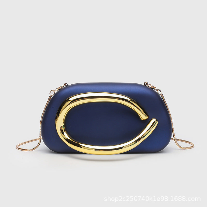 Kleine rechteckige Crossbody-Clutch mit abgerundeten Ecken, oversized poliertem C-förmigem Goldgriff und schmalem Goldkettenriemen, Detailansicht
