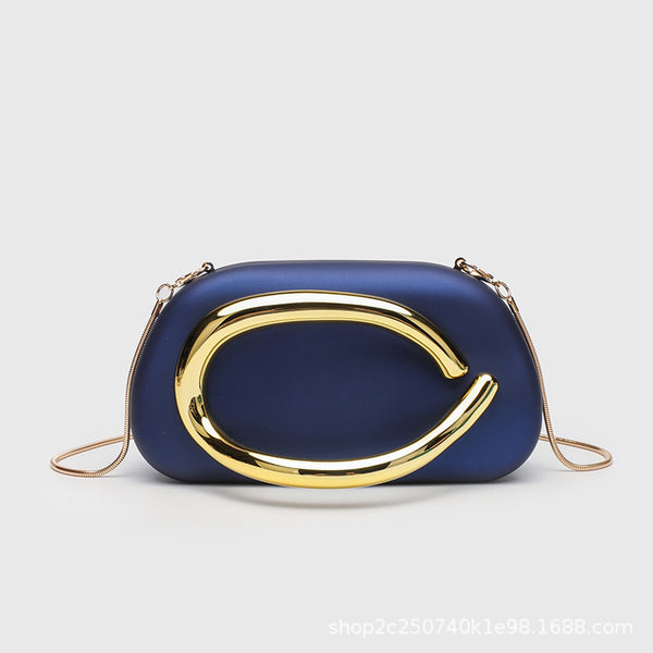 Kleine rechteckige Crossbody-Clutch mit abgerundeten Ecken, oversized poliertem C-förmigem Goldgriff und schmalem Goldkettenriemen, Detailansicht