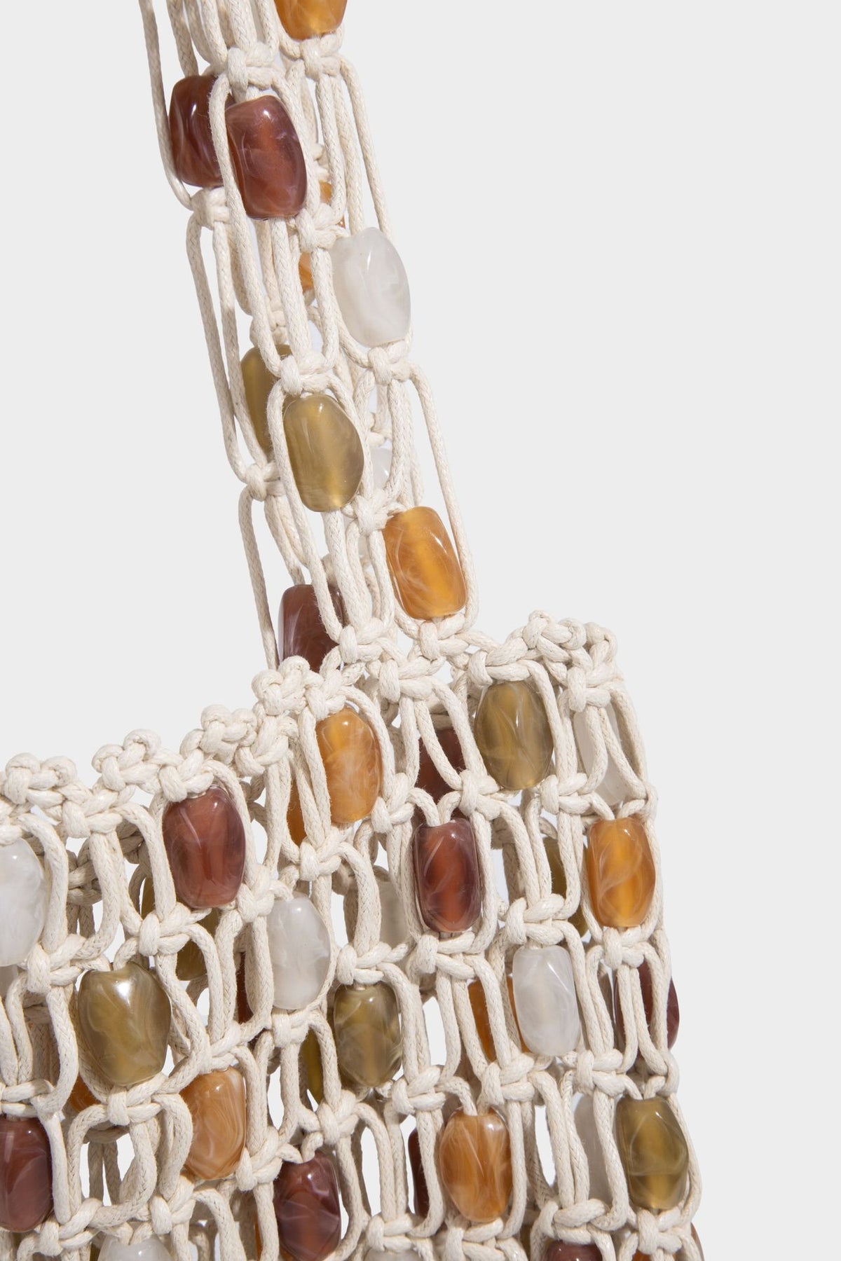 Cream macramé open-weave tote bag with multicolor amber olive and translucent bead accents and woven shoulder straps, detail