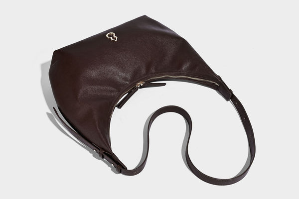 Lässig fallende, sichelförmige Hobo-Schultertasche in glatter dunkelbrauner Lederoptik mit Logo-Anhänger in Goldoptik und verstellbarem Schulterriemen