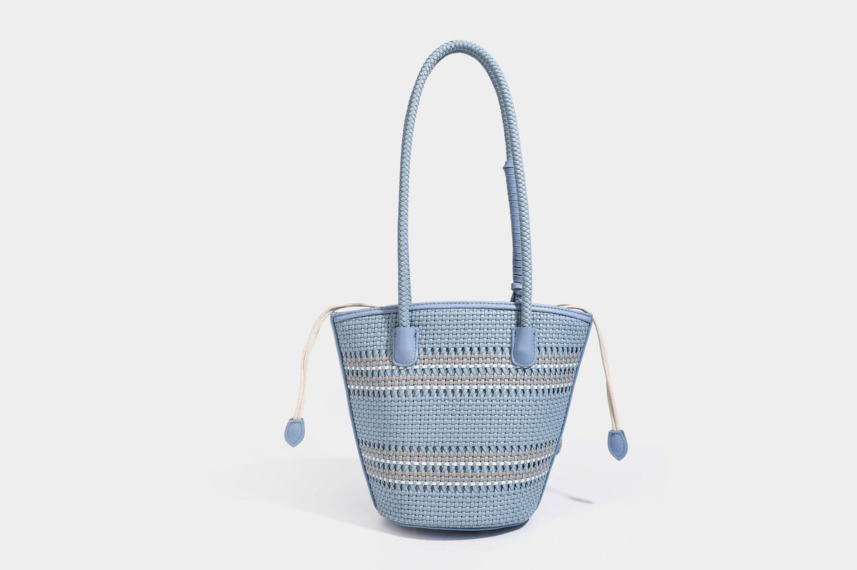 Light blue open-weave woven bucket tote bag with long braided shoulder straps, drawstring side ties, and attached mini pouch