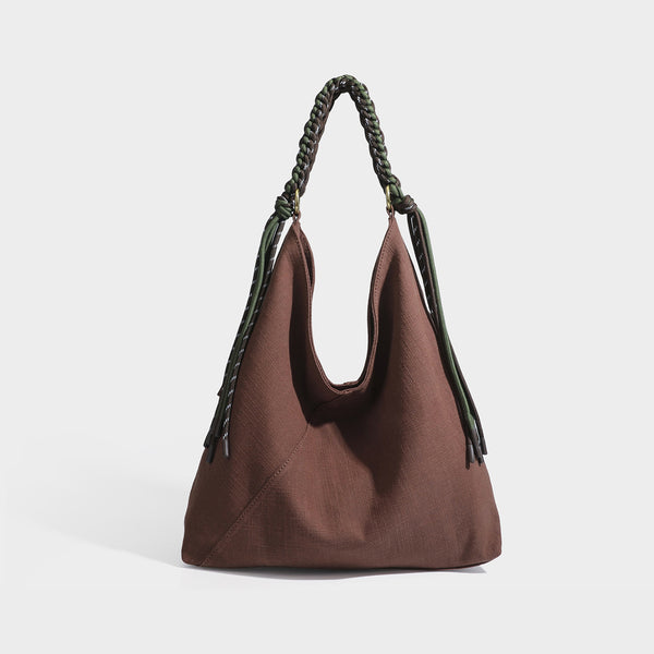 Soft slouchy cream canvas shoulder tote with braided brown and green cord handle, gold-tone ring hardware, and tassel trim