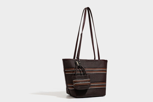 Large structured woven tote bag with striped basket-weave finish, long shoulder straps, and detachable mini pouch charm