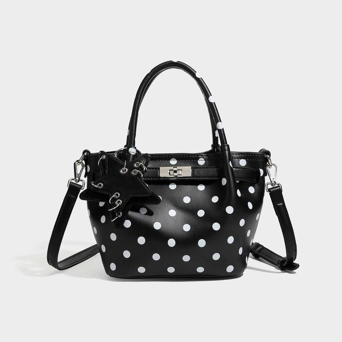 Small structured polka-dot mini tote bag in brown with white dots, star charm, dual top handles, and detachable shoulder