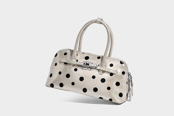 Glossy structured polka-dot satchel bag with dual top handles, silver turn-lock hardware, and detachable shoulder strap