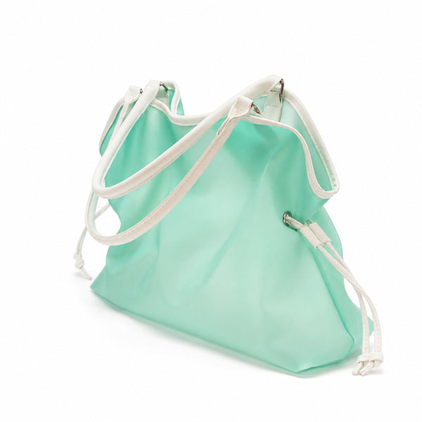 Glänzende mintfarbene Tote-Bag in Jelly-Optik mit weißem Besatz in Lederoptik, gewelltem oberen Rand und silberfarbenem Stern-Spiegelanhänger an einer Kugelkette