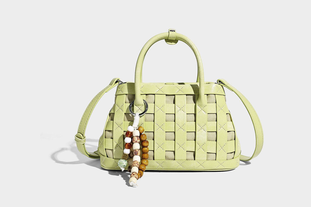 Small structured woven satchel tote with rounded top handles, silver-tone ring hardware, and bead tassel charm, detail view