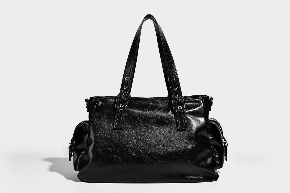 Glossy structured black tote shoulder bag with silver buckle hardware, zip pockets, dual top handles, and detachable, detail