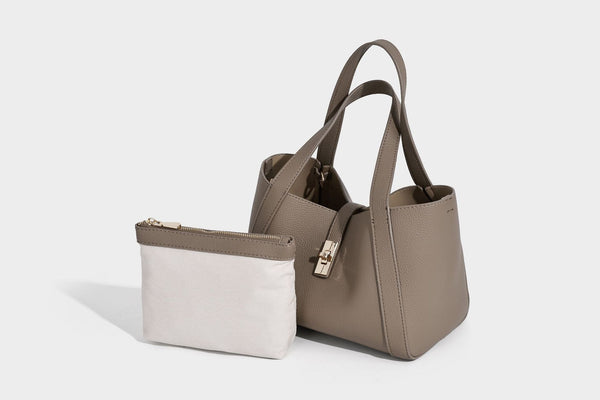 Structured trapezoid tote bag in taupe pebbled leather-look finish with gold-tone turn-lock hardware, dual top handles, and