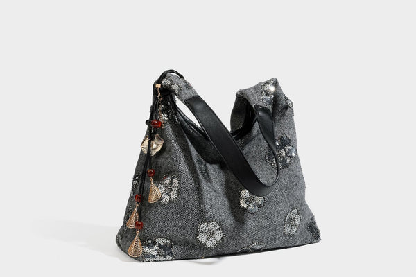 Lässig fallende, trapezförmige Schulter-Tote in Anthrazitgrau mit floralen Paillettenmotiven in Silber, Riemen in Lederoptik und herabhängendem Perlenbesatz