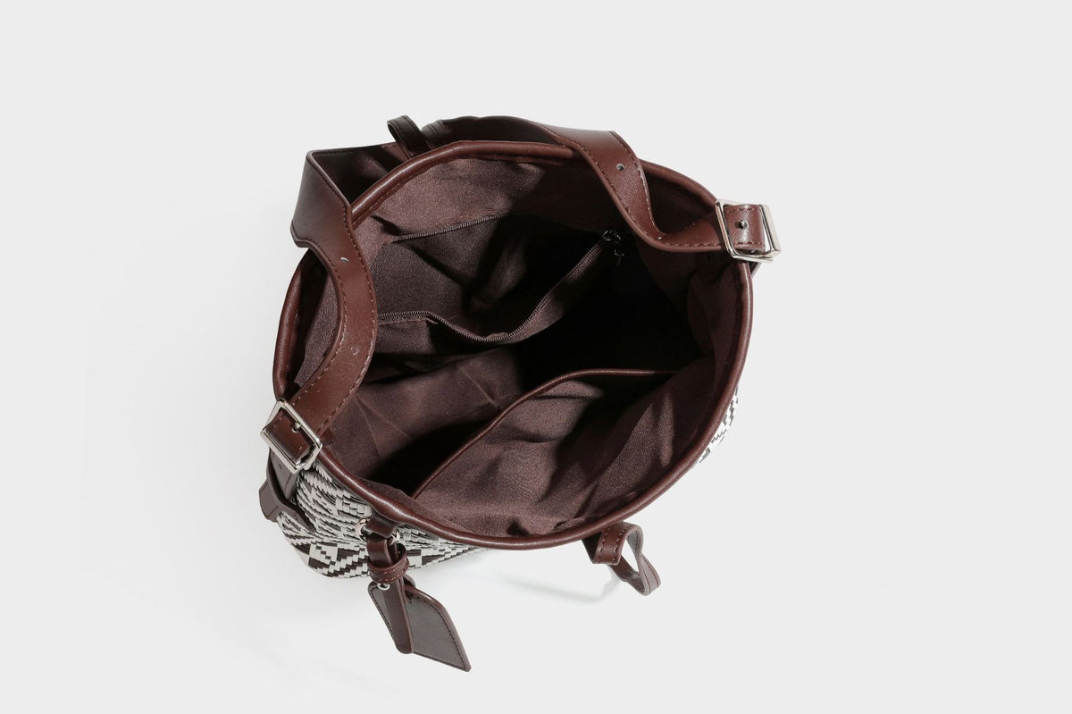 Woven geometric bucket shoulder bag in white and dark brown two-tone pattern with leather-look trim and drawstring top