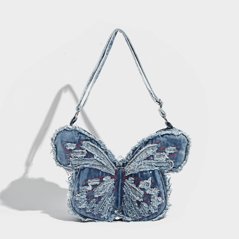 Butterfly-shaped distressed denim shoulder bag with frayed raw edges and embroidered wing panels, detail view 6