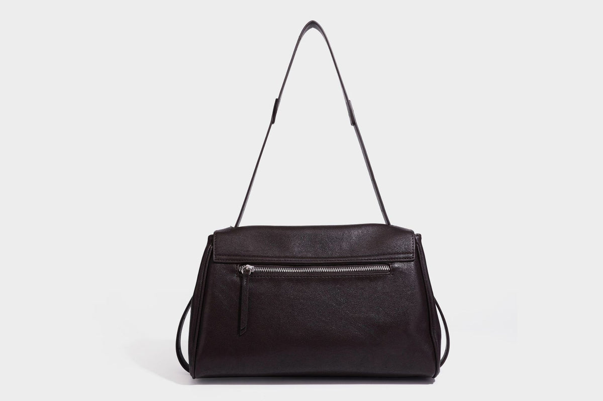 Strukturierte rechteckige dunkelbraune Schultertasche in Lederoptik mit Klappe, mehrlagigem Detail auf der Vorderseite und langem verstellbarem Riemen, Detailansicht