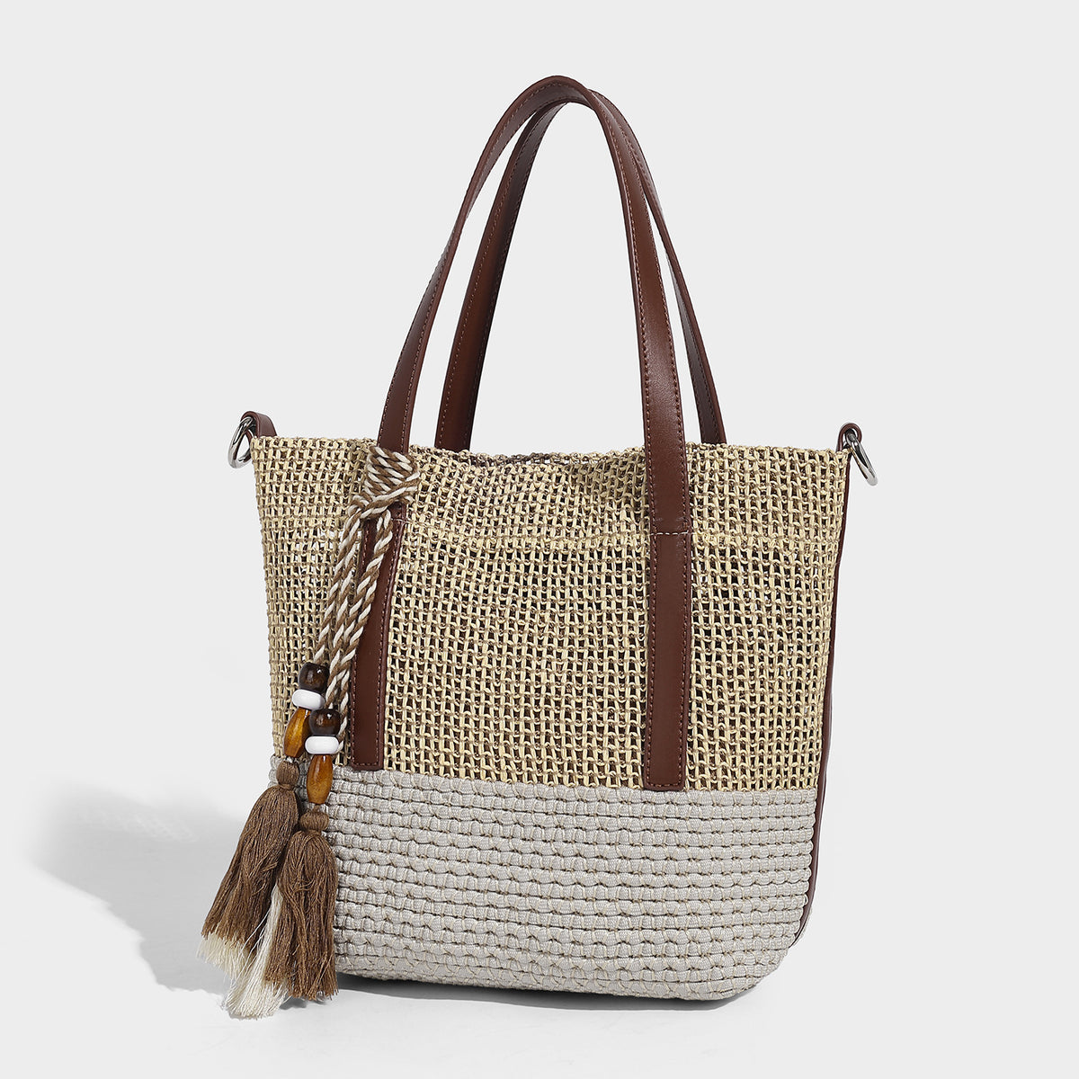 Two-tone open-weave tote bag in beige and cream with brown leather-look handles, tassel bead charm, and detachable