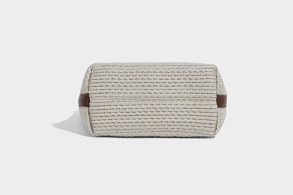 Two-tone open-weave tote bag in beige and cream with brown leather-look handles, tassel bead charm, and detachable