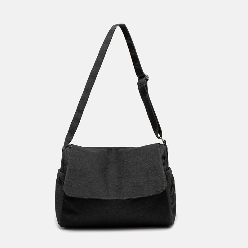Große Messenger-Bag aus mattem schwarzem Canvas mit Frontklappe, Reißverschluss oben, elastischen Seitentaschen und verstellbarem silberfarbenem