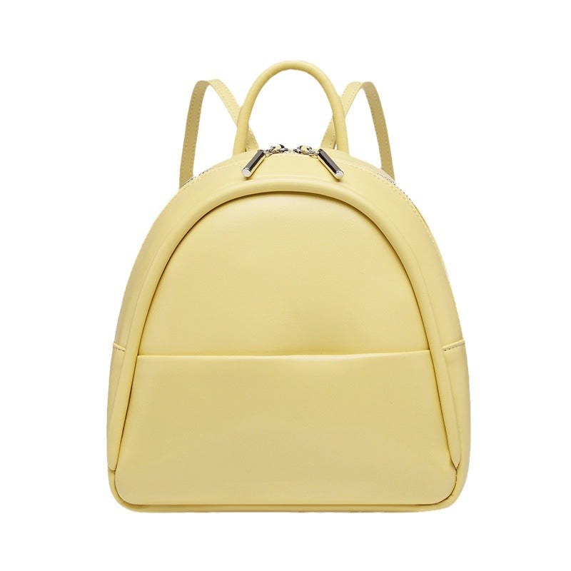 Kleine kuppelförmige Mini-Rucksackhandtasche in Pastellgelb mit glatter Oberfläche in Lederoptik, bogenförmigem Reißverschluss oben und silberfarbenen Details