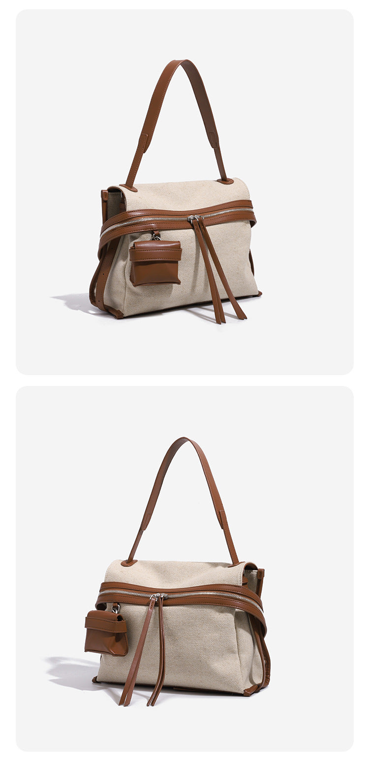 Cream canvas zip-top shoulder bag with cognac leather-look trim, dual zipper, attached mini pouch, and tassel strap ties