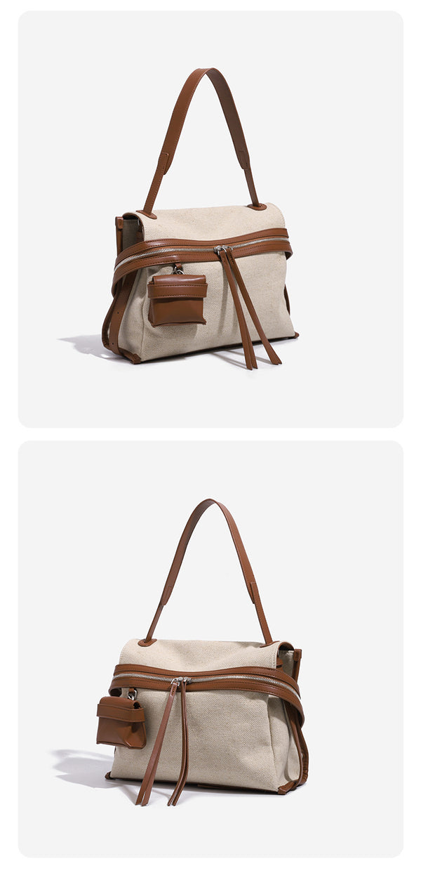 Cream canvas zip-top shoulder bag with cognac leather-look trim, dual zipper, attached mini pouch, and tassel strap ties