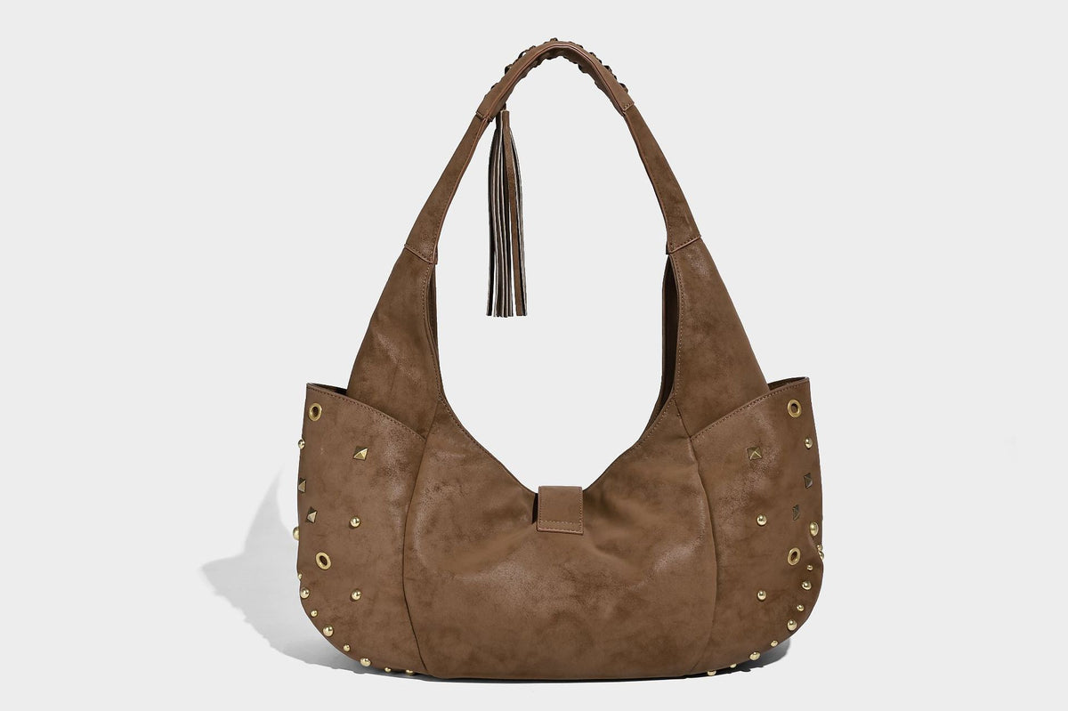 Slouchy crescent hobo bag in matte brown suede-like finish with gold-tone studs, grommets, braided top handle, tassel side