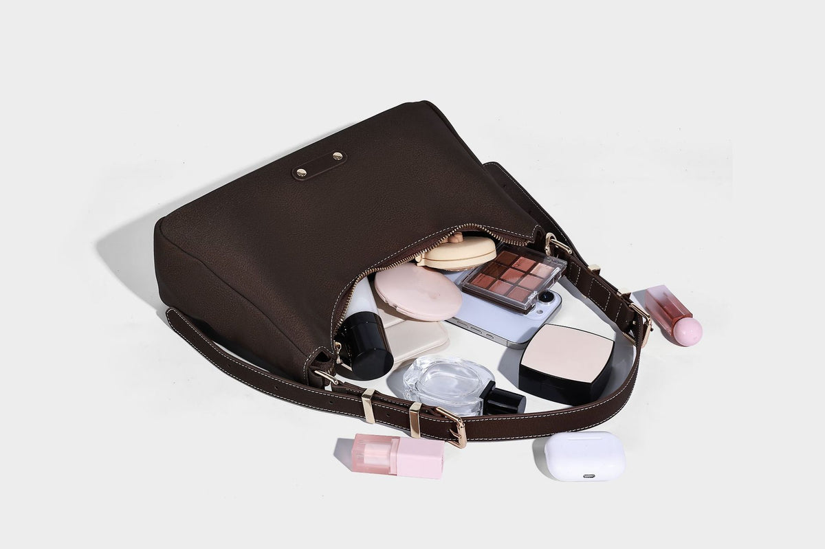 Crescent hobo shoulder bag in pebbled leather-look finish with top zipper, adjustable strap, gold-tone ring hardware, and