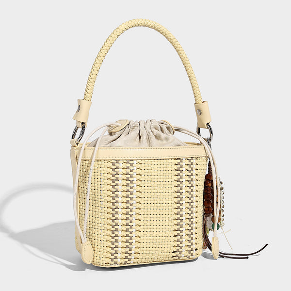 Small woven bucket bag with drawstring top, braided handle, detachable crossbody strap, and silver-tone ring hardware, detail