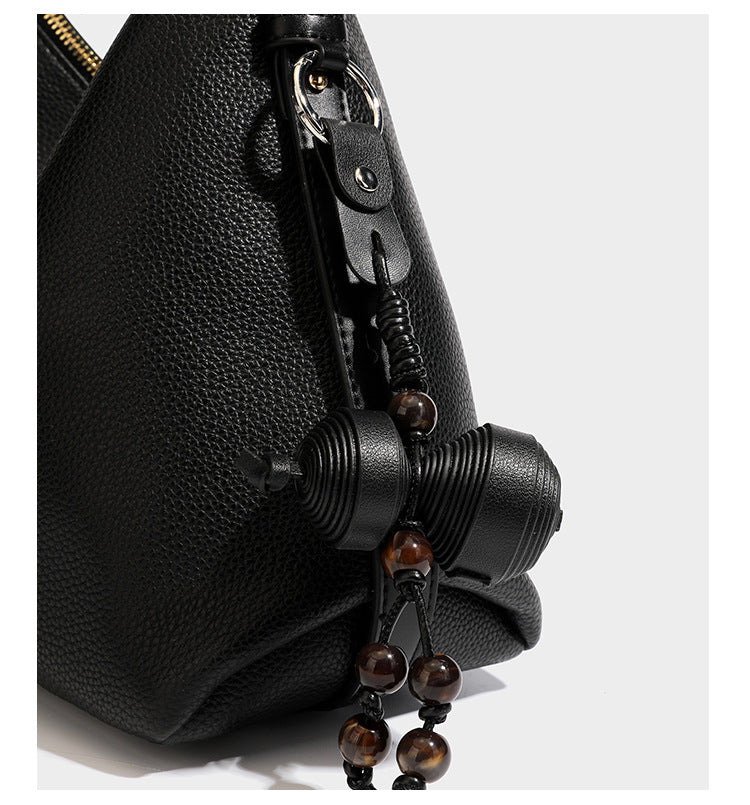 Slouchy hobo shoulder bag with pebbled leather-look finish, zip-top closure, gold-tone hardware, and hanging bead charm