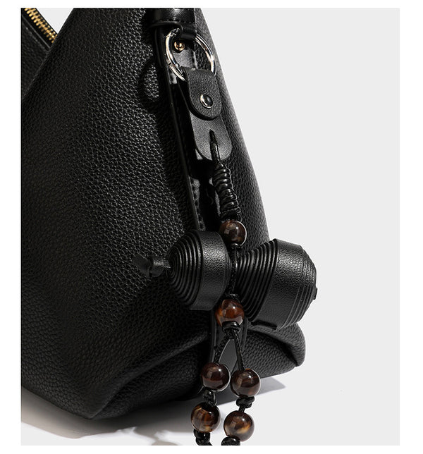 Slouchy hobo shoulder bag with pebbled leather-look finish, zip-top closure, gold-tone hardware, and hanging bead charm
