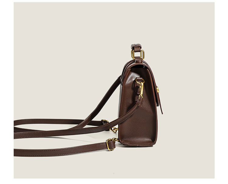 Structured mini satchel backpack with smooth leather-look finish, front flap pocket, gold-tone stud closures, and top handle