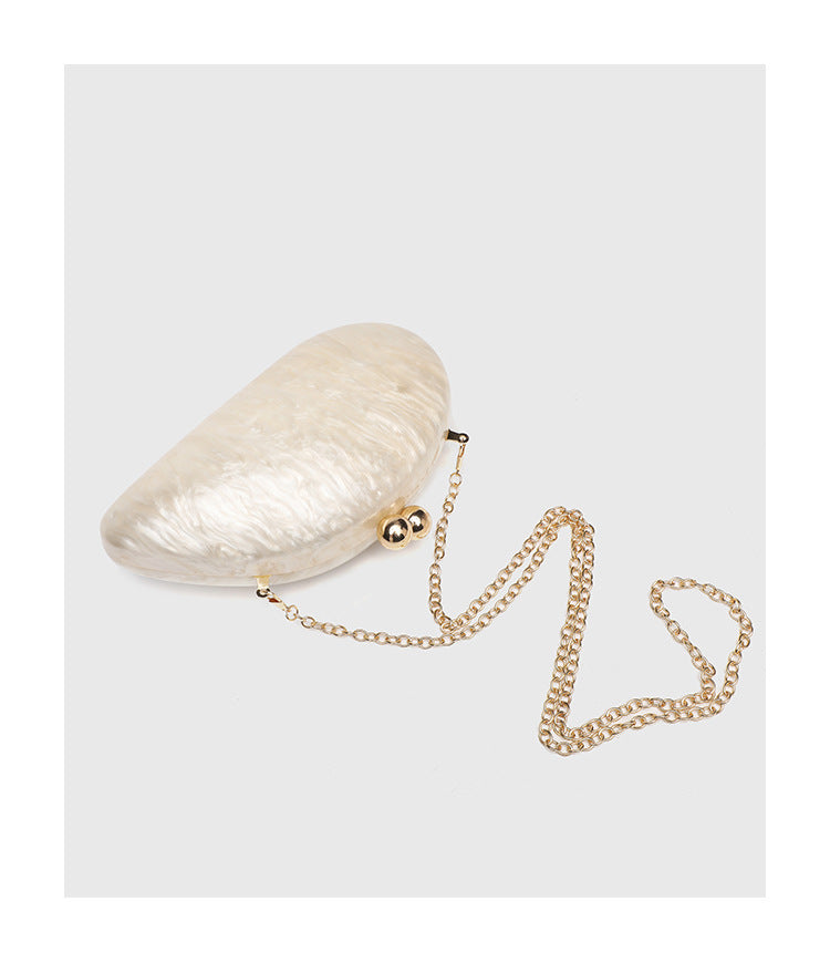 Ovale Hartschalen-Clutch in marmorierter Perlmuttoptik mit Verschluss aus zwei goldfarbenen Kugeln und goldfarbener Kettenriemen, Detailansicht