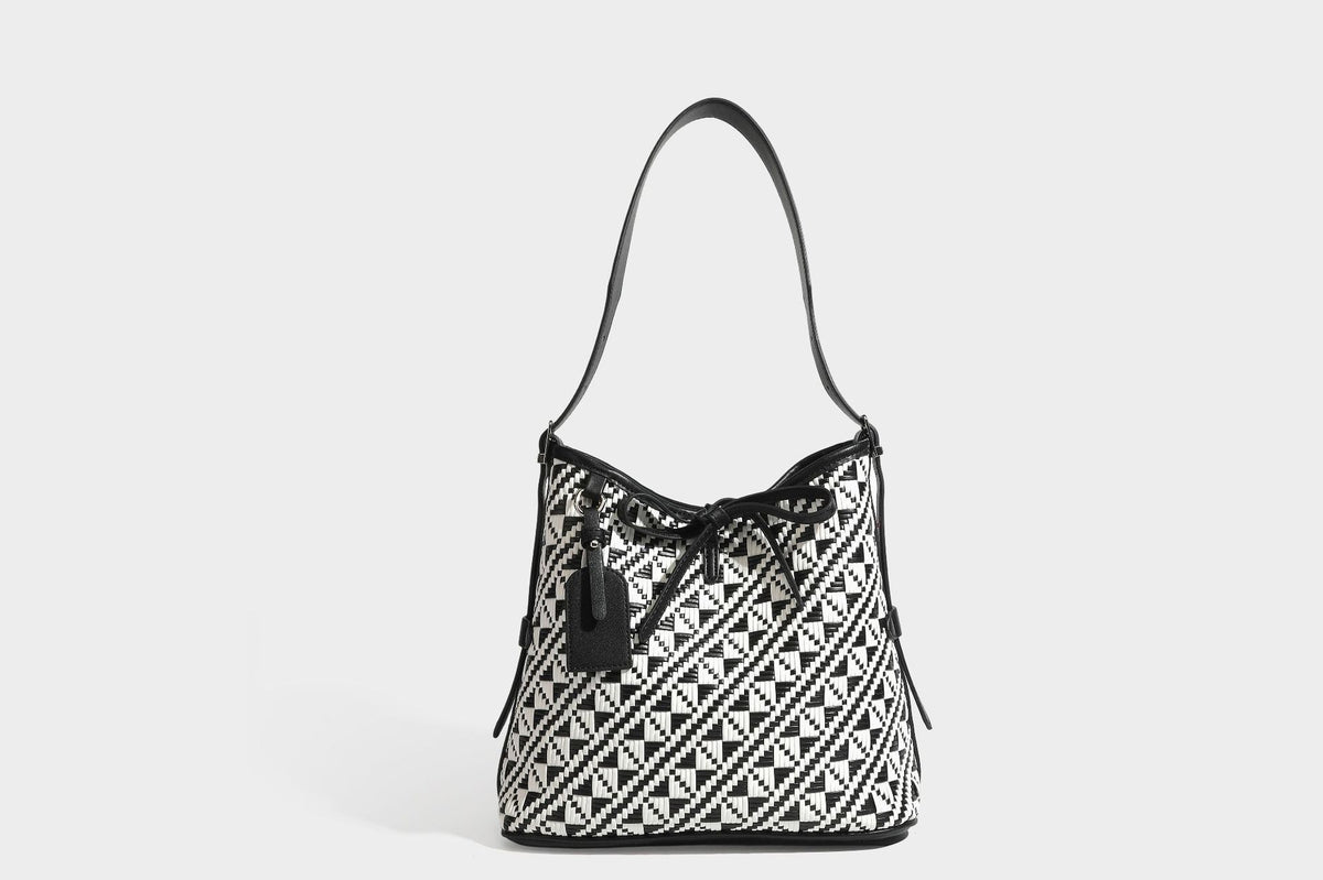 Woven geometric bucket shoulder bag in white and dark brown two-tone pattern with leather-look trim and drawstring top