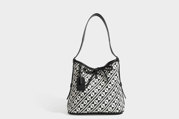 Woven geometric bucket shoulder bag in white and dark brown two-tone pattern with leather-look trim and drawstring top