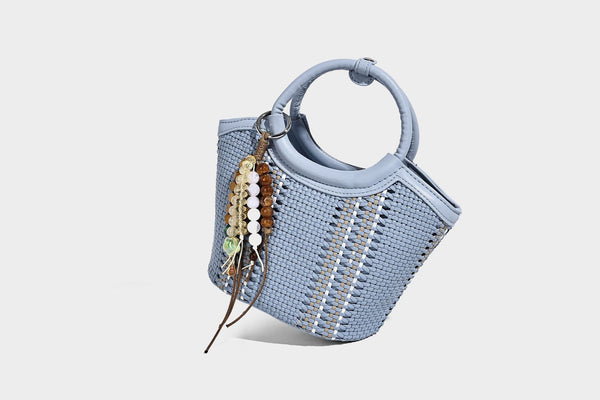 Kleine strukturierte Beuteltasche aus geflochtenem Material mit rundem Tragegriff in Lederoptik, silberfarbenen Beschlägen und perlenbesetztem Quastenanhänger, Detail