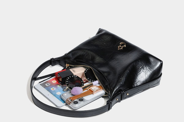 Übergroße, lässig fallende Hobo-Schultertasche aus glänzendem, geknittertem Material in Lederoptik mit Reißverschluss und Emblem-Beschlägen in Goldoptik, Detailansicht