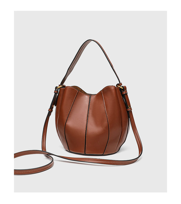 Smooth leather-look paneled bucket bag in brown with wide woven shoulder strap, gold-tone ring hardware, and detachable zip