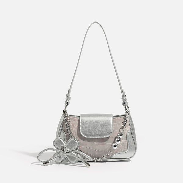 Compact silver flap shoulder bag with pale-pink crocodile-embossed panel, chain bead handle, bow charm, and adjustable, front