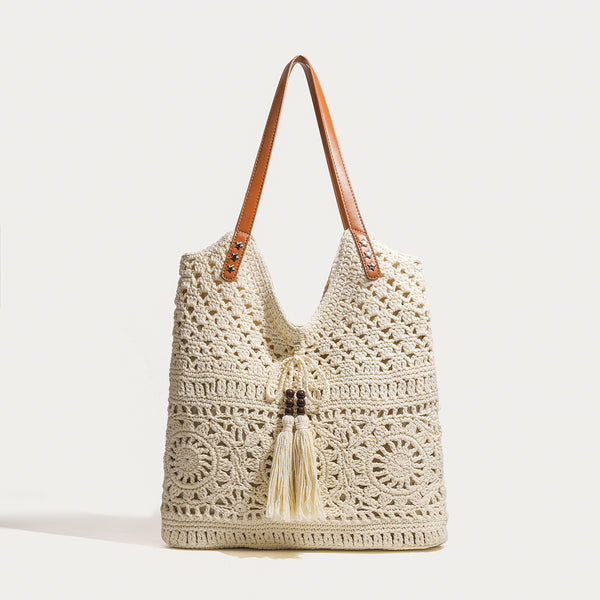 Cream openwork crochet tote bag with tan leather-look double shoulder straps and tassel drawstring tie, detail view 6