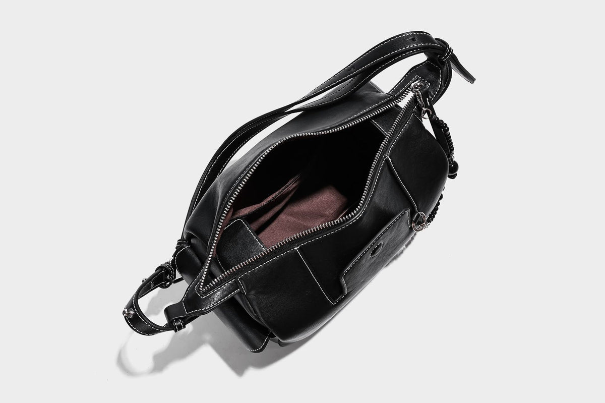 Small slouchy moto-style crossbody bag in smooth matte leather-look finish with white contrast stitching, silver-tone, detail