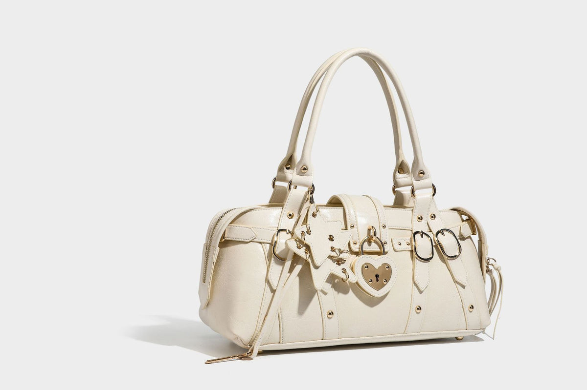 Glossy dark brown structured Boston satchel with heart-shaped lock charm, star pendant, rivet studs, multi-strap front panel