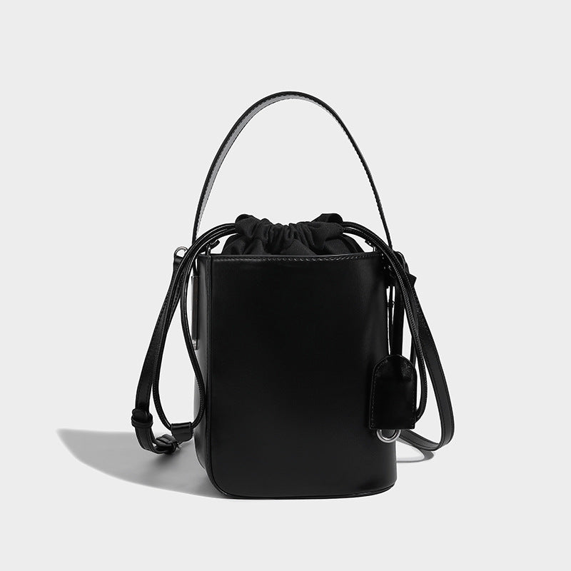Small structured drawstring bucket bag in smooth matte leather-look finish with rigid top handle and detachable shoulder